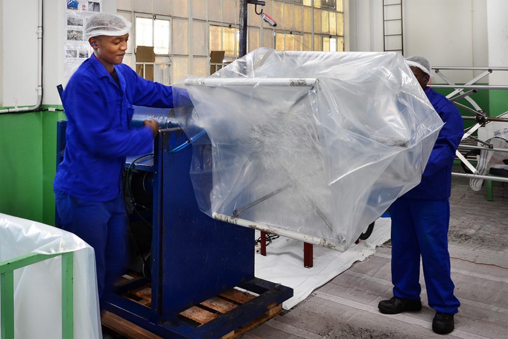 Custom Bulk Bag employees fitting an inner liner into a bulk bag