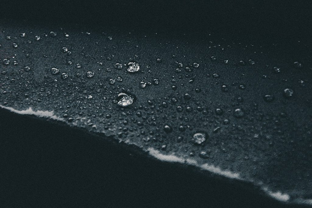 Water droplets on surface of black woven fabric