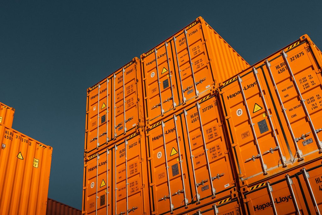 Bright orange shipping containers against a dark blue sky