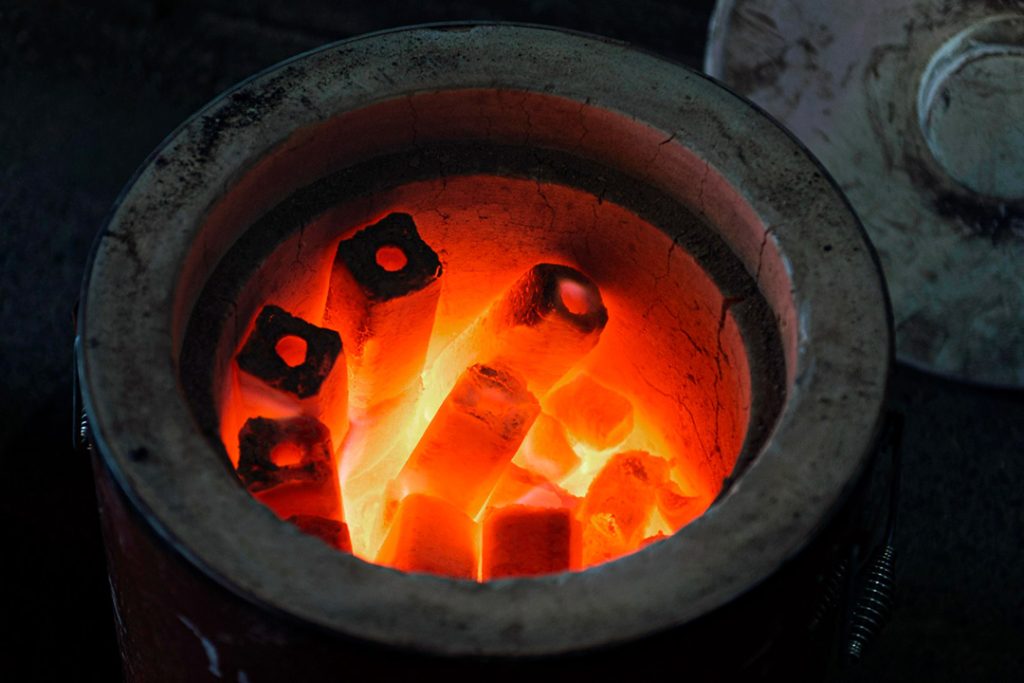 A circular furnace at extreme temperature with iron rods melting inside.