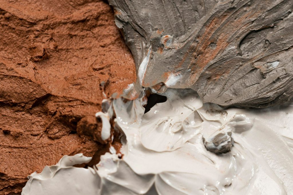Three piles of damp product; one brown clay, one grey cement and one white plaster.