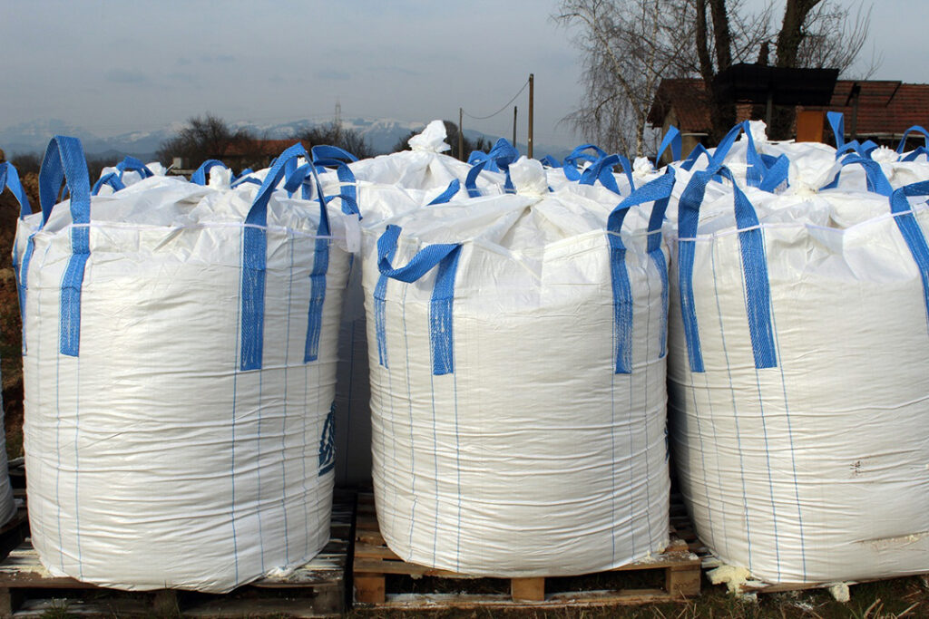 Three bulk bags on wooden pallets outside.