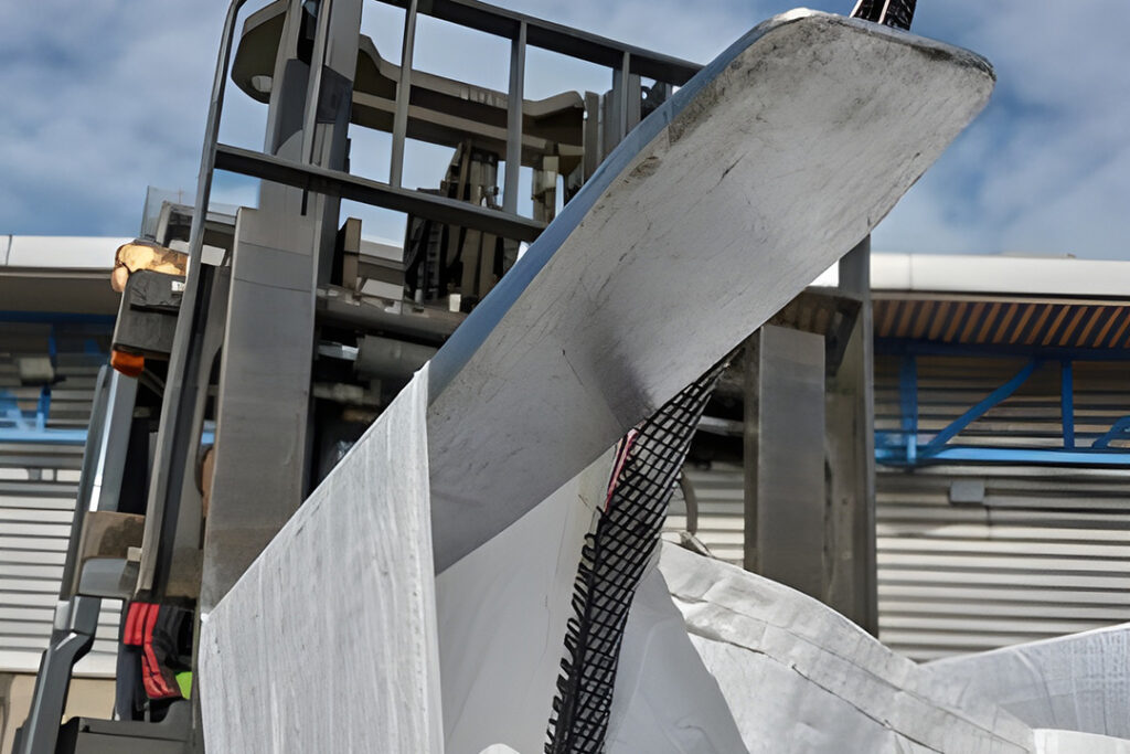 Forklift tines penetrating tunnel sleeves on a white bulk bag