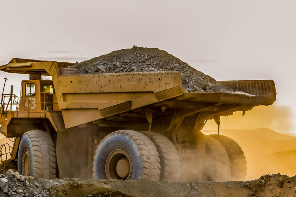 A large mining dumper driving in the sunset on a copper mine.