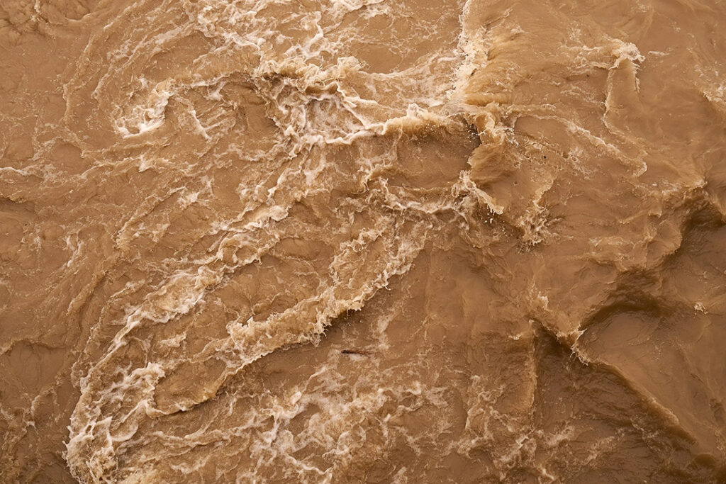 Muddy brown turbulent flood water.