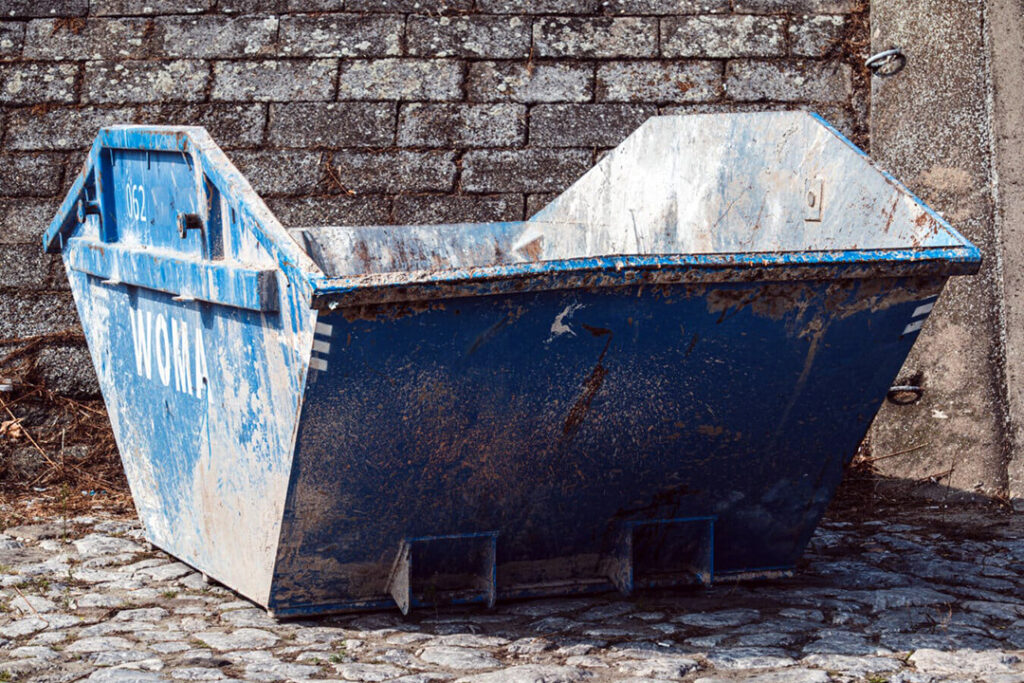 An empty blue waste management skip in a cobblestone alley