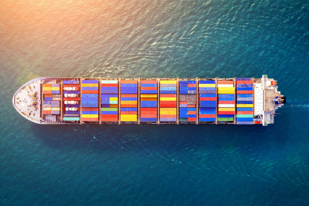 A top-down aerial view of a large ship with colourful containers on board.
