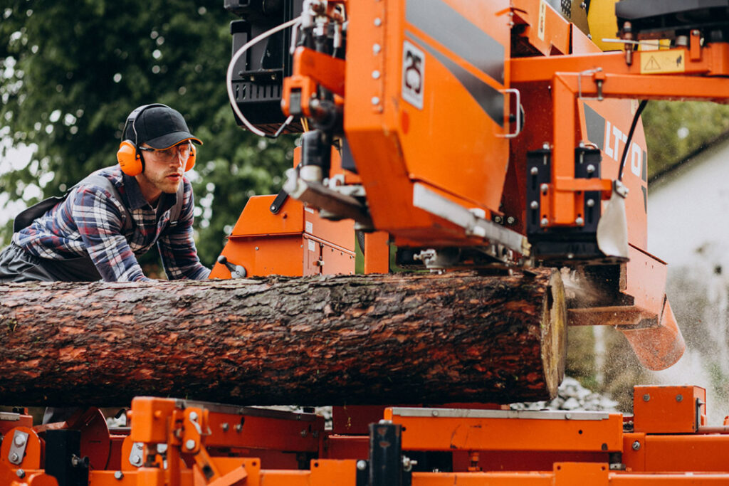A man using a sawmill to cut a pine log