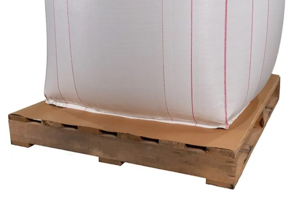 A slip sheet on a wooden pallet underneath a white bulk bag