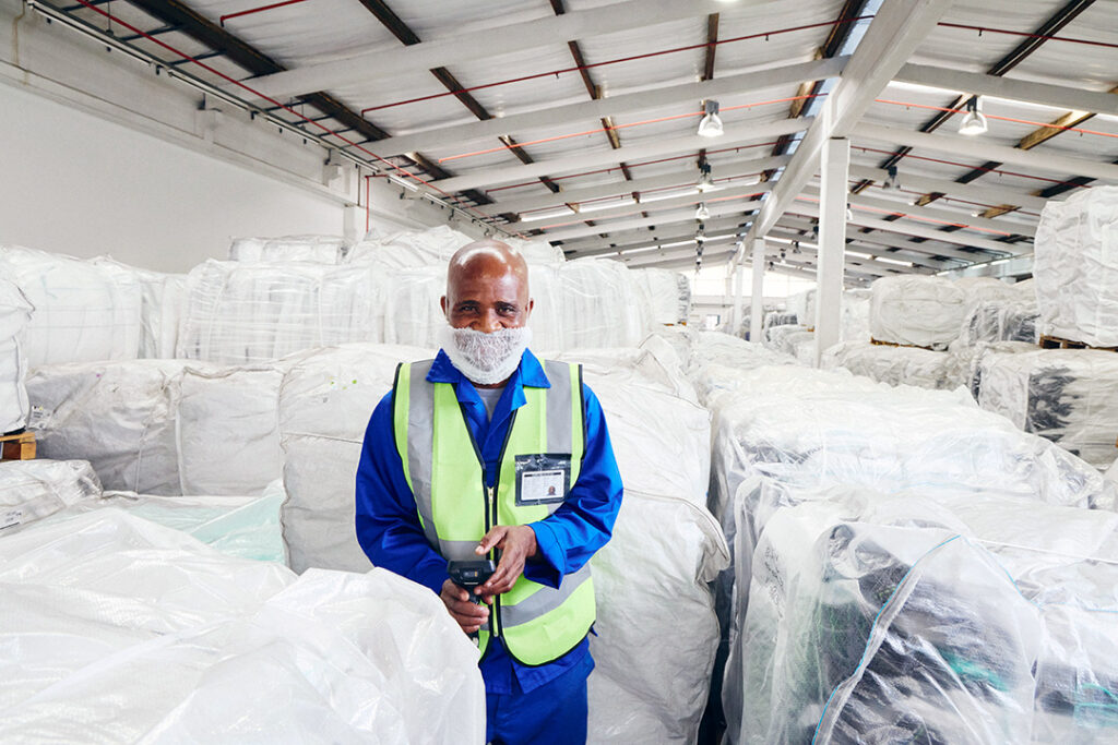 A worker from CBB is standing amongst empty bulk bags in a storage warehouse.