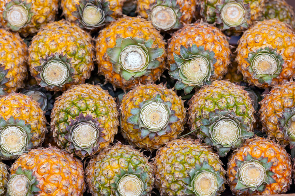 An organised bunch of prepared pineapples in a retail store.