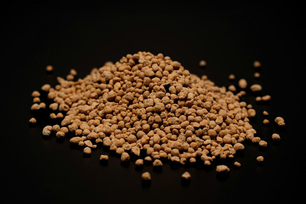 Small brown granules of fertiliser on a black background.