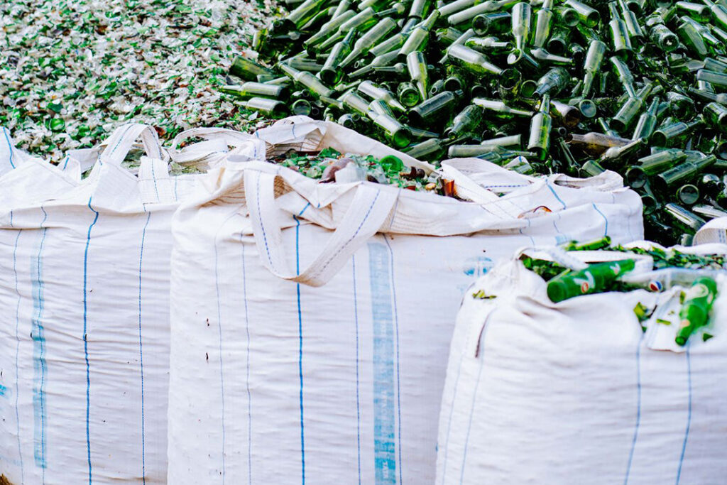 Bulk bags at a waste management site filled with green glass bottles