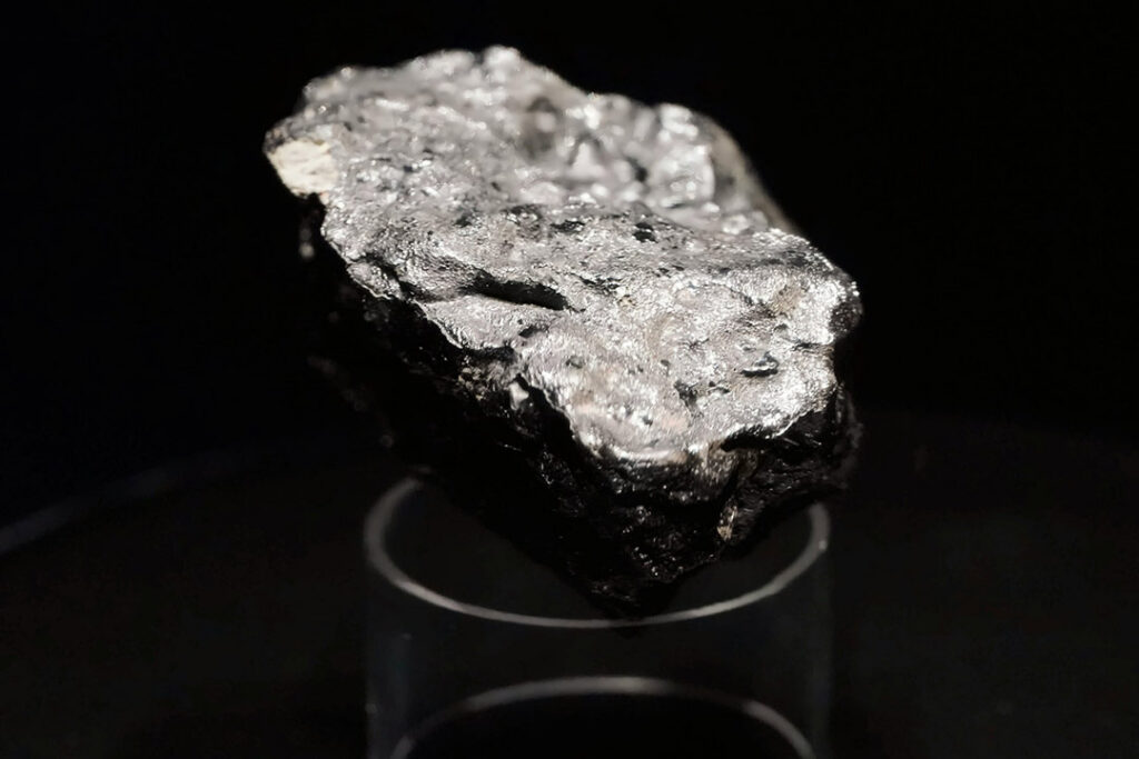 A silvery piece of titanium ore on a black background